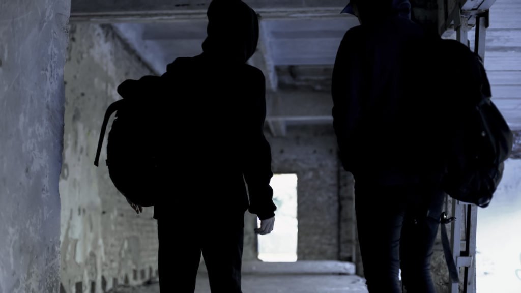 Dos ladrones con capuchas y mochilas en camino para cometer un robo