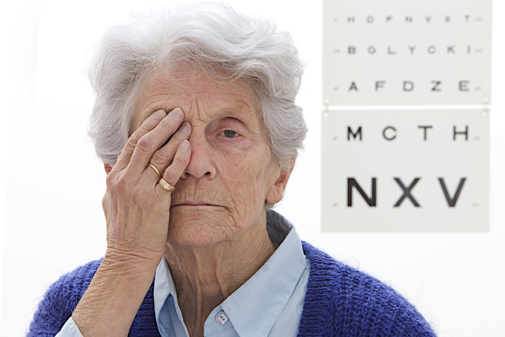 Older person taking an eye exam for a driver's license renewal.