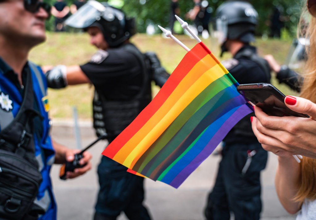 Police at gay pride parade with rainbow flag in the foreground