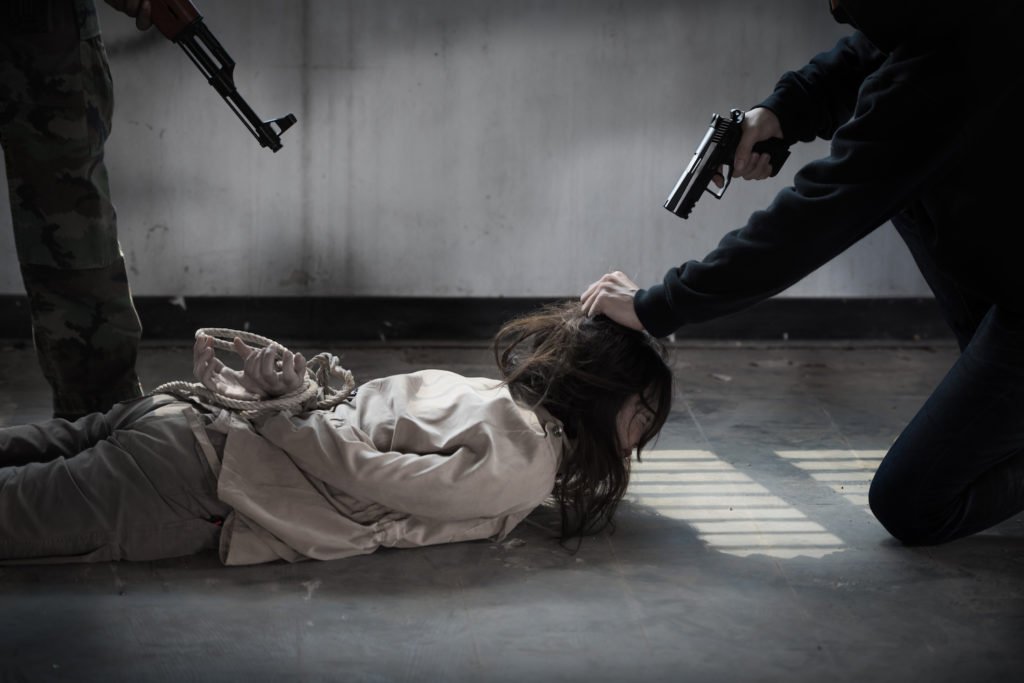 Two men with guns holding down a victim on the floor in an act of kidnapping that will be felony murder if they kill her