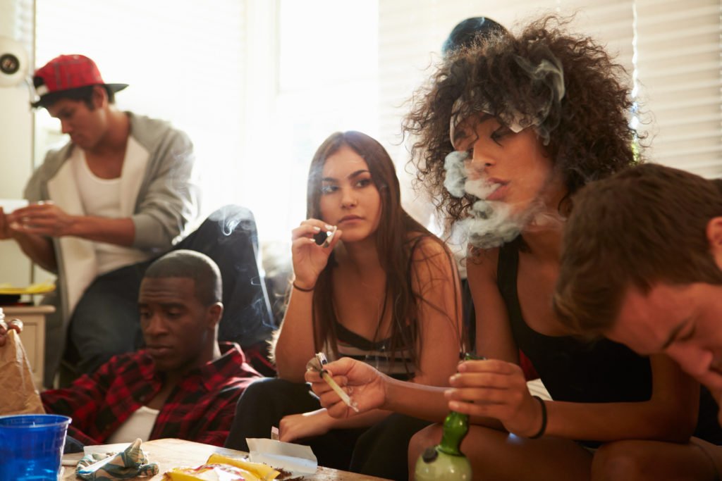 Five young people consuming various controlled substances in a drug house