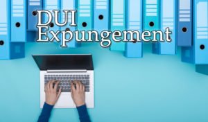Fingers typing on laptop keyboard and sign that reads "DUI expungement"