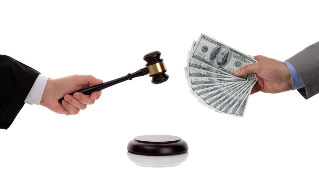 Judge's hand holding gavel and a defendant's hand holding fine money - a violation of Vehicle Code 10501 VC carries a fine of up to $1000.00
