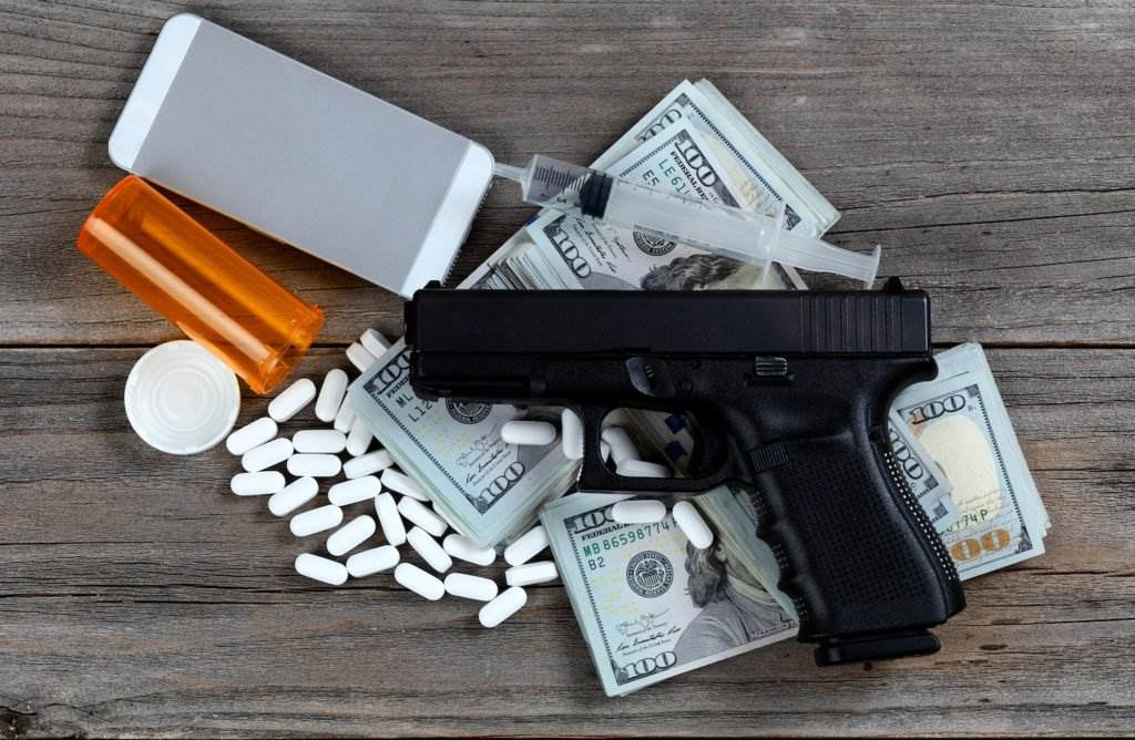 Pills, phone, syringe, revolver, and wads of $100-bills