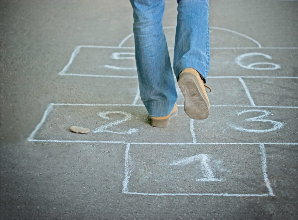 Adult legs walking over chalk hopscotch board in park