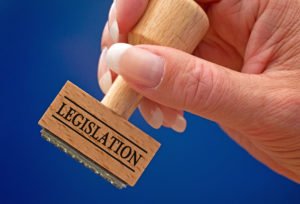 Hand holding rubber stamp that says legislation
