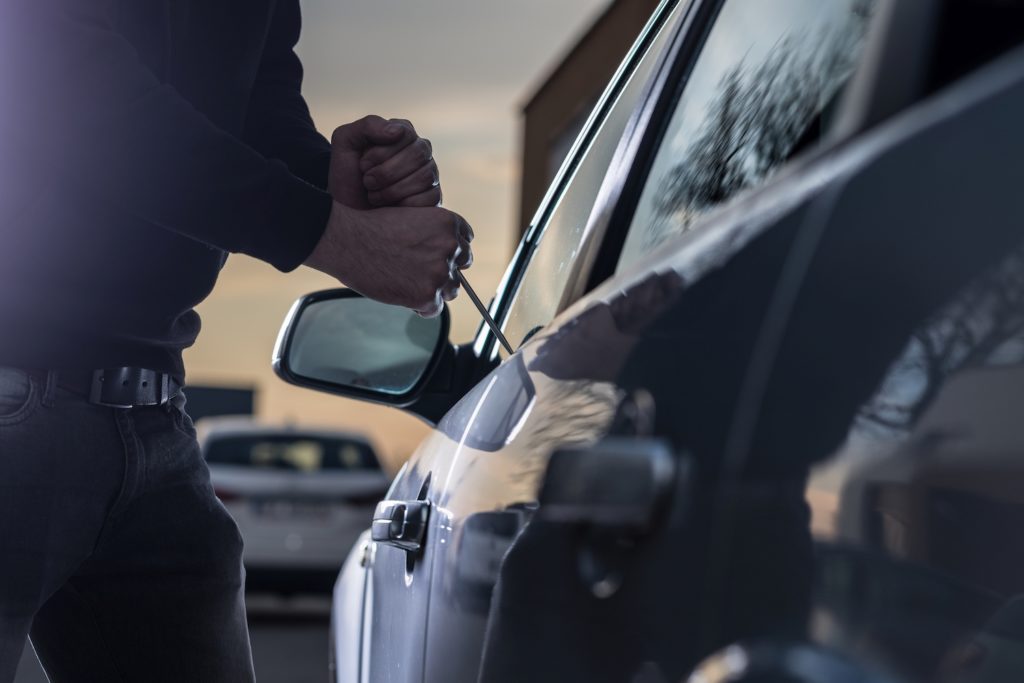 Hombre usando un delgado Jim para entrar en un coche como ejemplo de gran robo de un vehículo motorizado según la ley de Nevada NRS 205.228