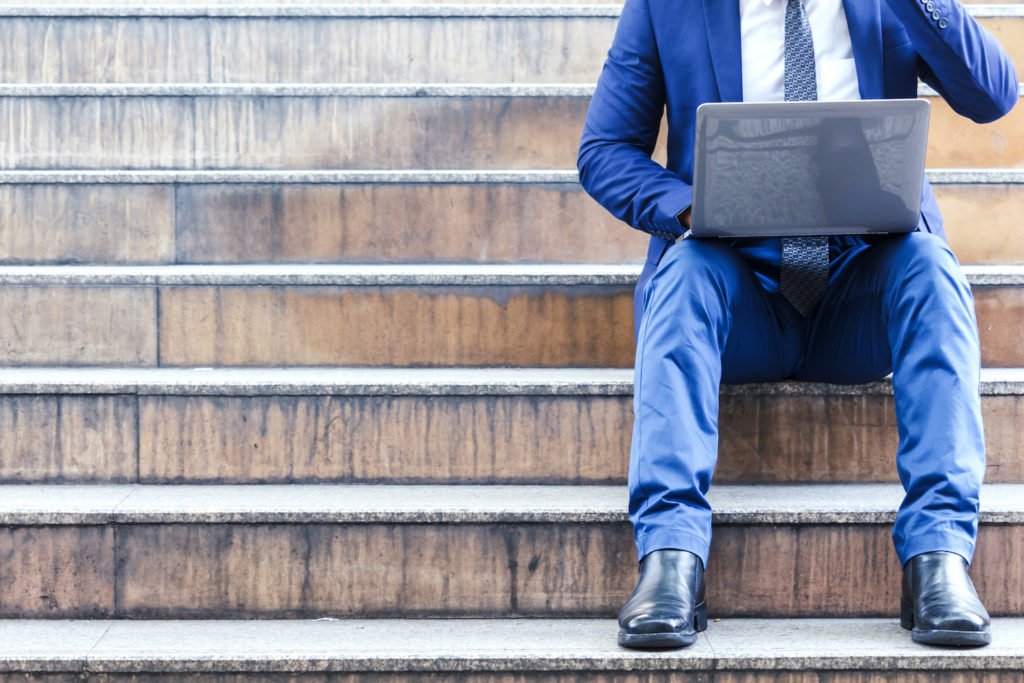 Person with laptop sitting on building steps