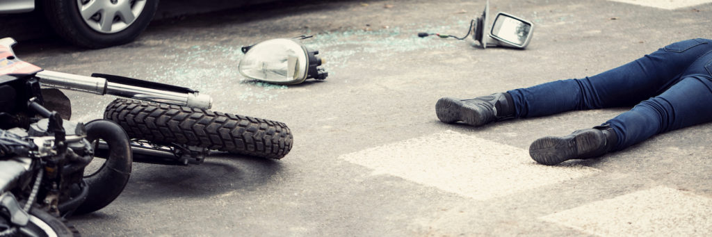 Aftermath of a motorcycle accident with a crashed bike and a body on the street