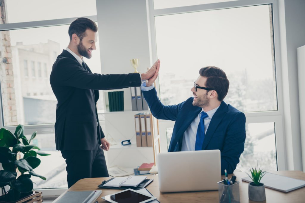 Two attorneys high-fiving at a desk