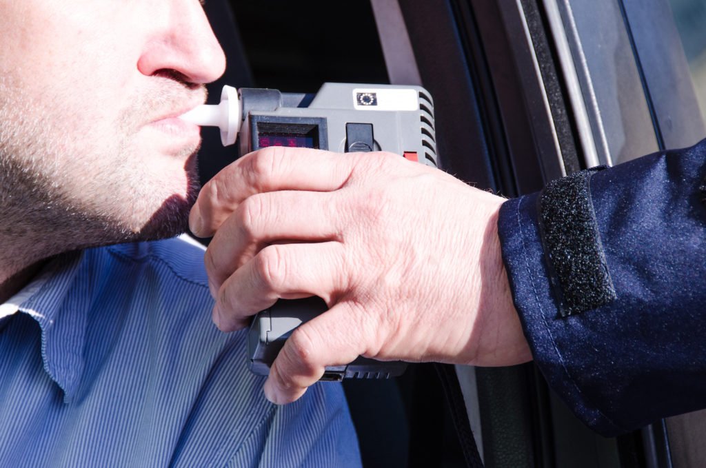 Hombre tomando prueba de aliento preliminar durante una parada de tráfico por DUI