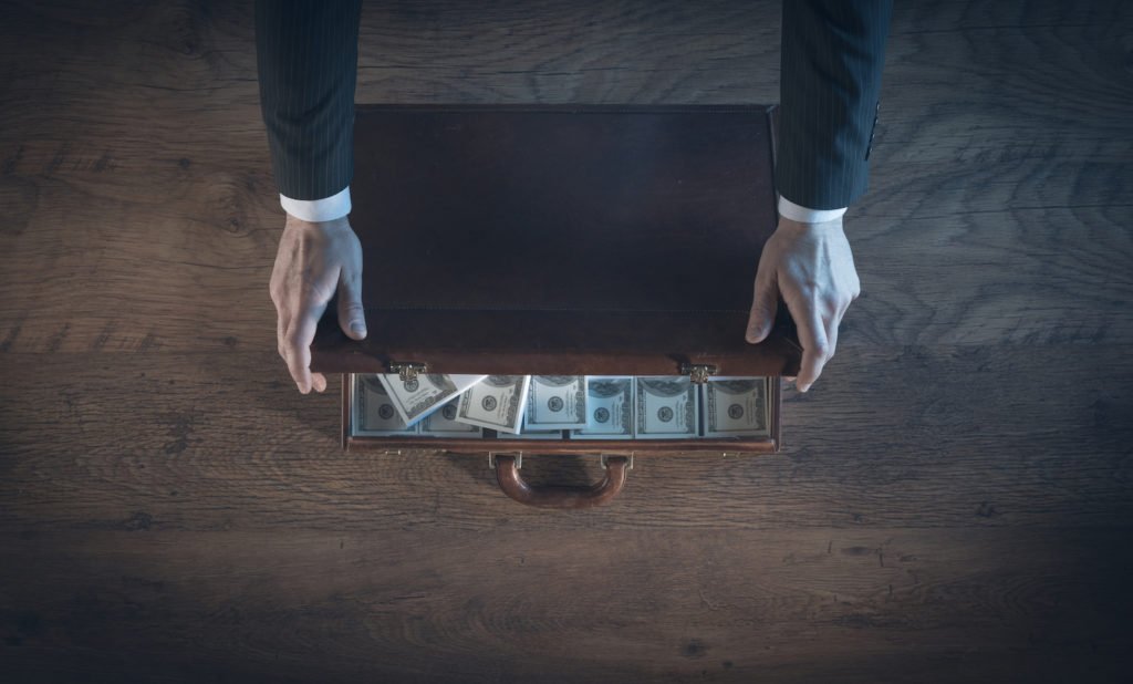 Two hands opening briefcase full of laundered cash