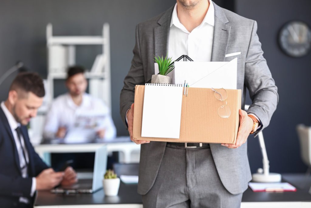Employee leaving office with box of personal belongings 