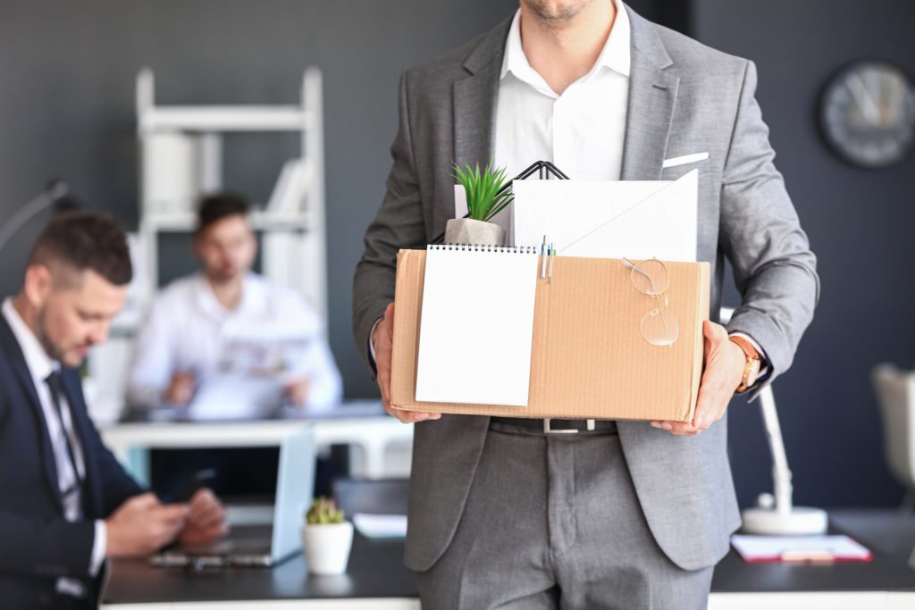 Empleado saliendo de la oficina con caja de pertenencias personales