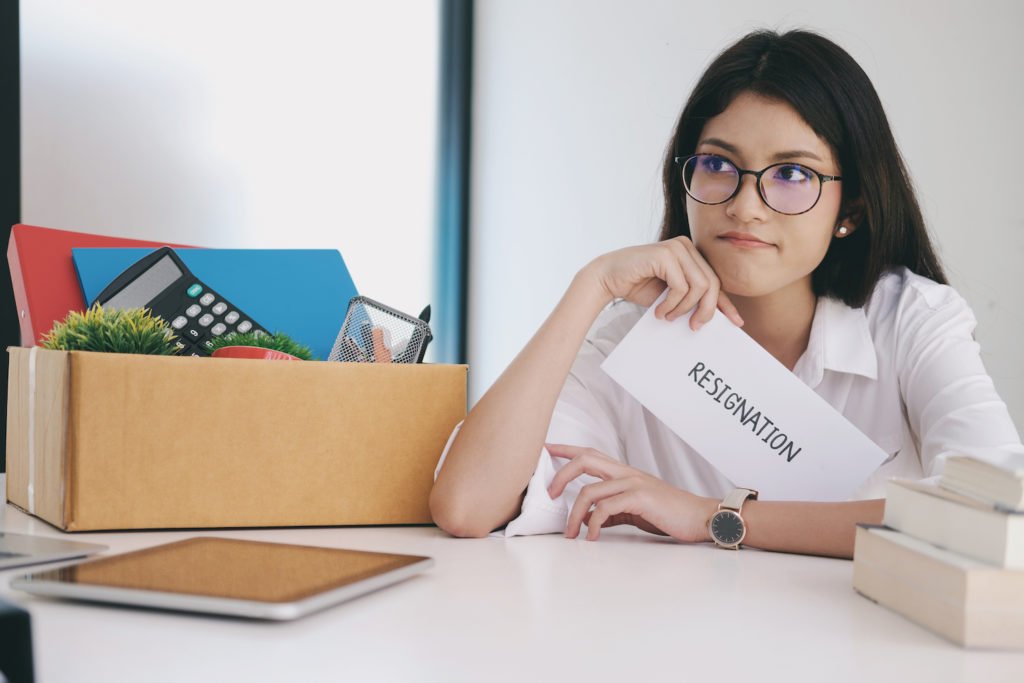 Employee holding resignation letter next to box of personal belongings