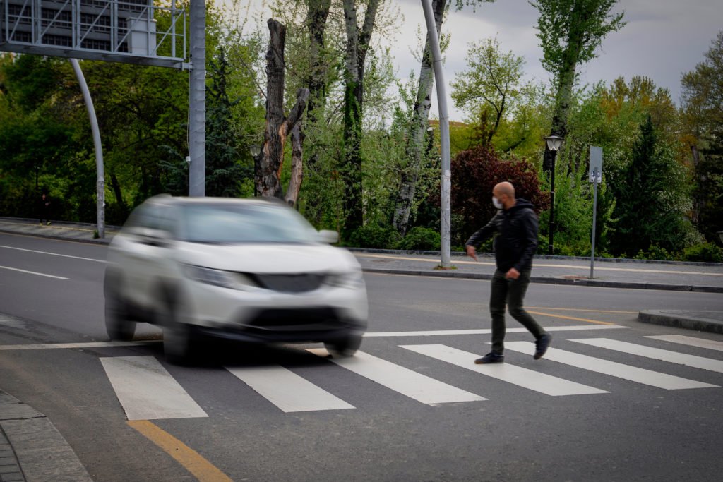 Un coche conduciendo a través de un paso de peatones a pesar de que hay un peatón cruzando