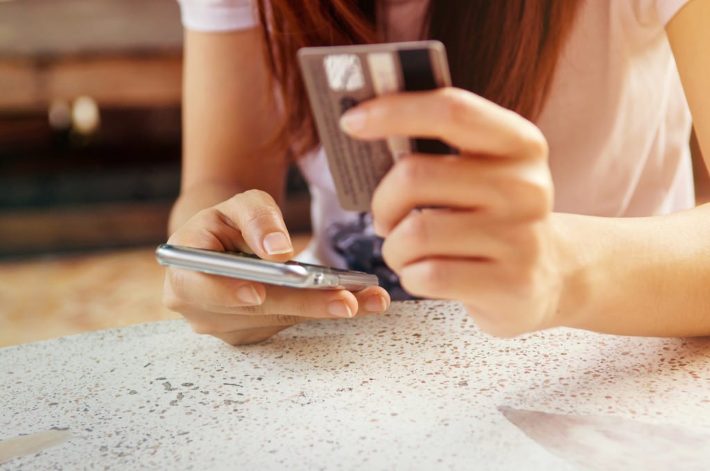 Closeup de una mujer sosteniendo una tarjeta de crédito y un teléfono