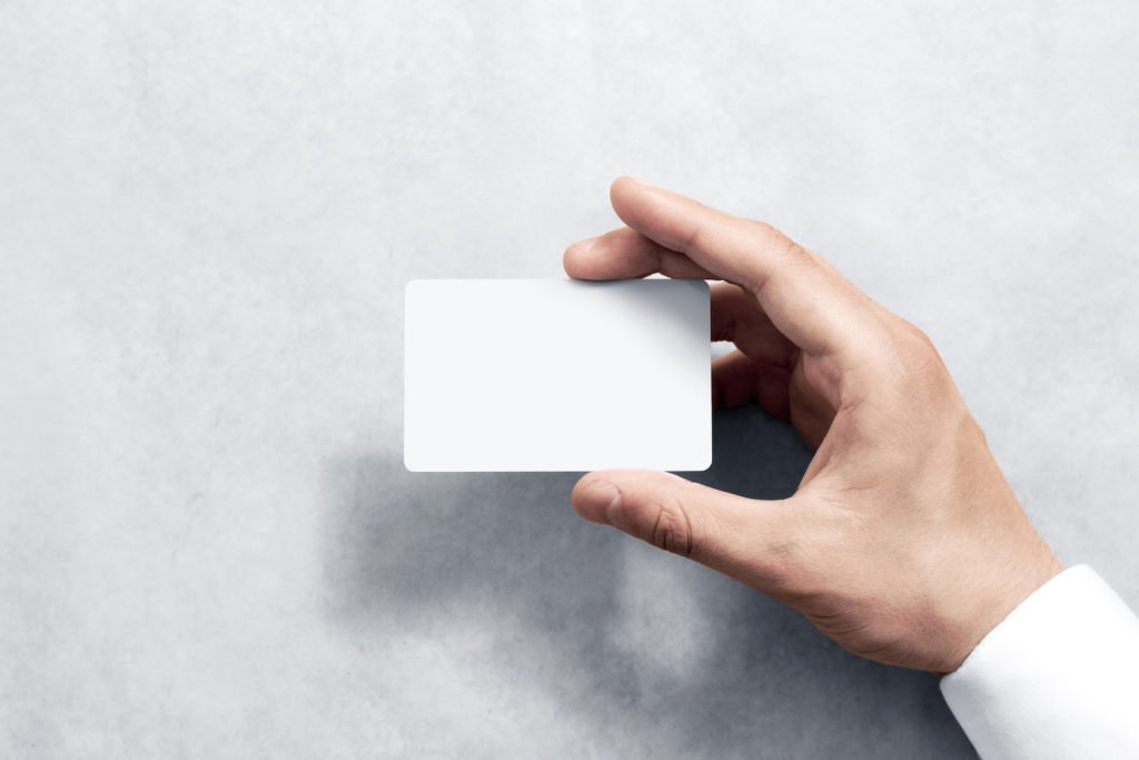 Mano de un hombre sosteniendo una tarjeta de crédito en blanco como ejemplo de uso ilegal de un dispositivo de transacción financiera en violación de CRS 18-5-702.
