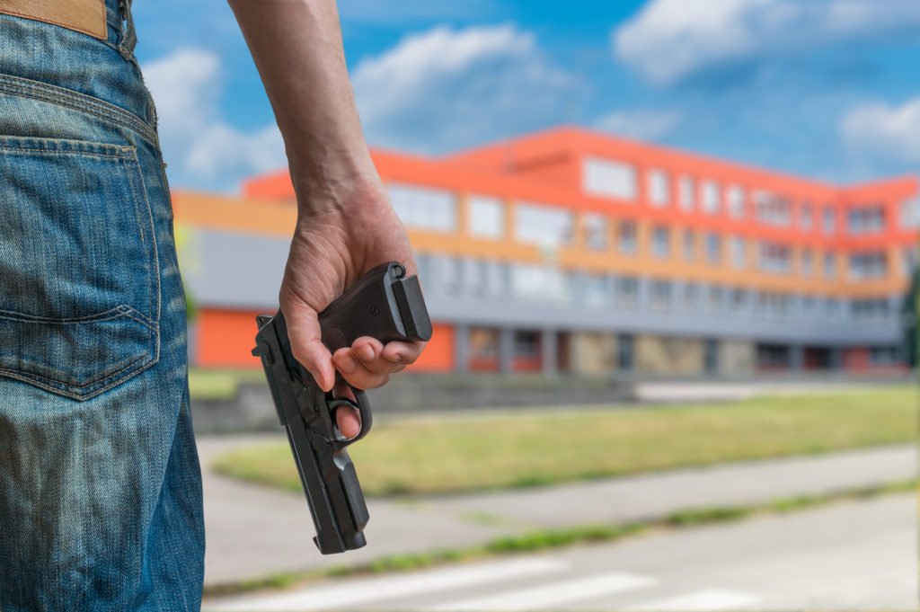 Closeup of man holding gun about to shoot into a building in violation of CRS 18-12-107.5