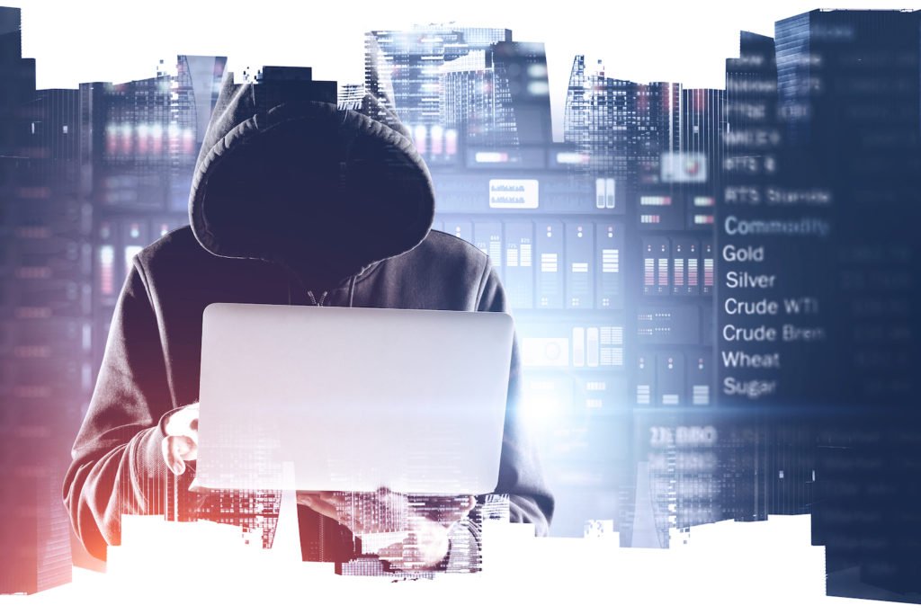 Hombre con capucha detrás de la computadora enfrente de un fondo que dice oro, plata, etc.