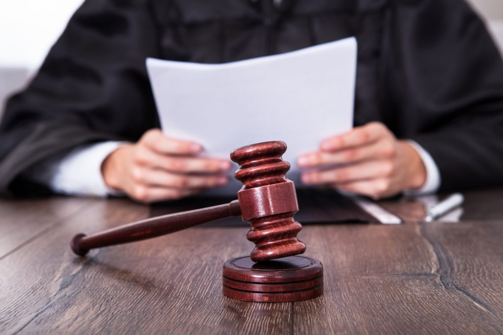 Judge holding paper behind a gavel on desk