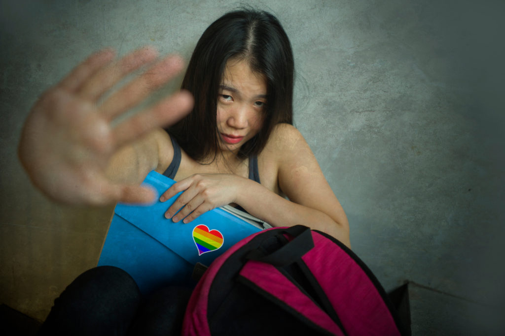 Mujer asiática gay sosteniendo su mano para desviar un ataque de delito de odio