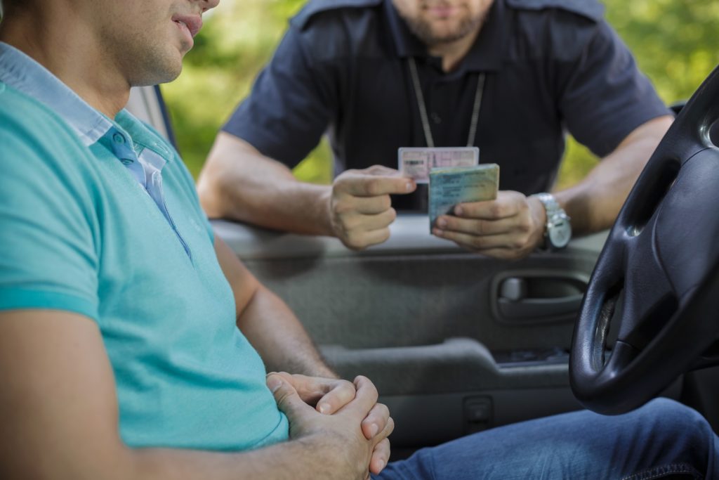 Policeman looking at driver's license during traffic stop.