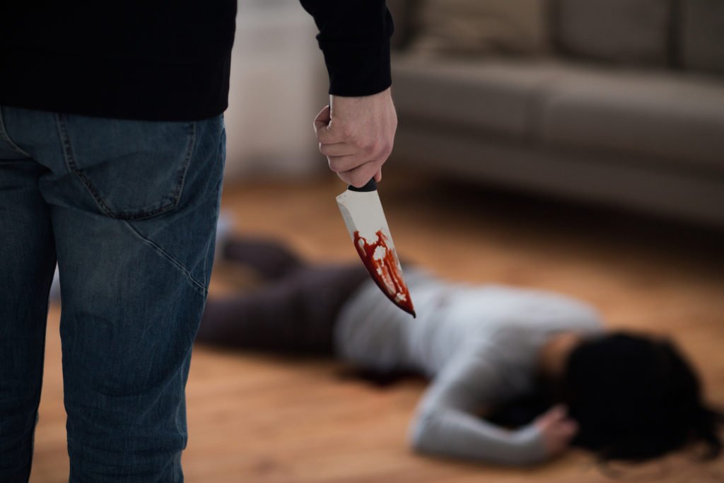 Man holding bloody knife over murder victim on floor