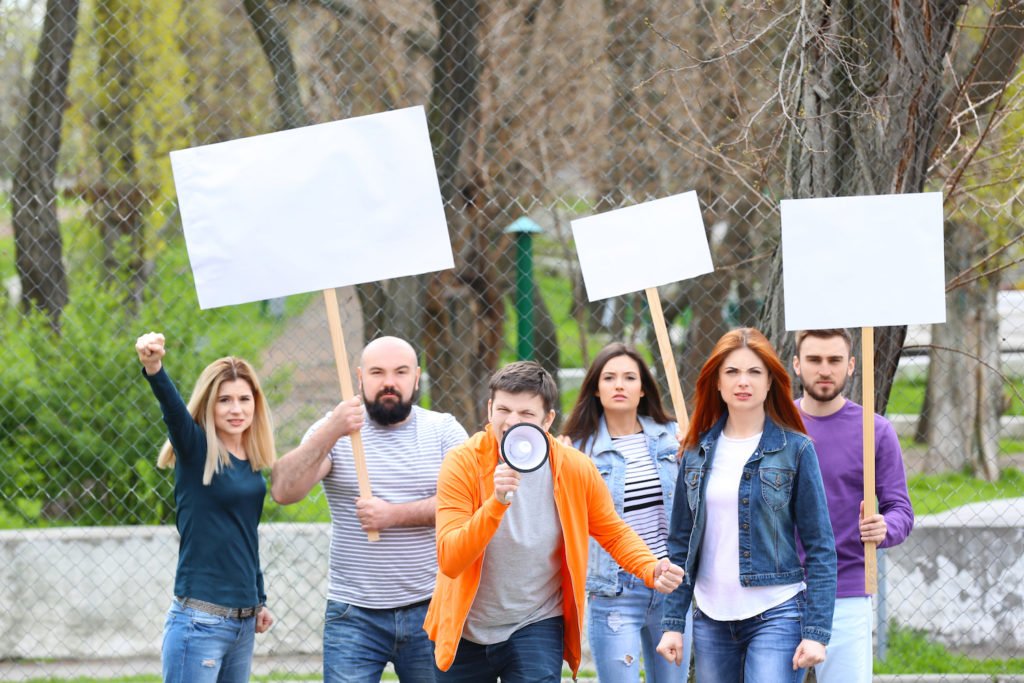 A protest with six people holding signs and a megaphone