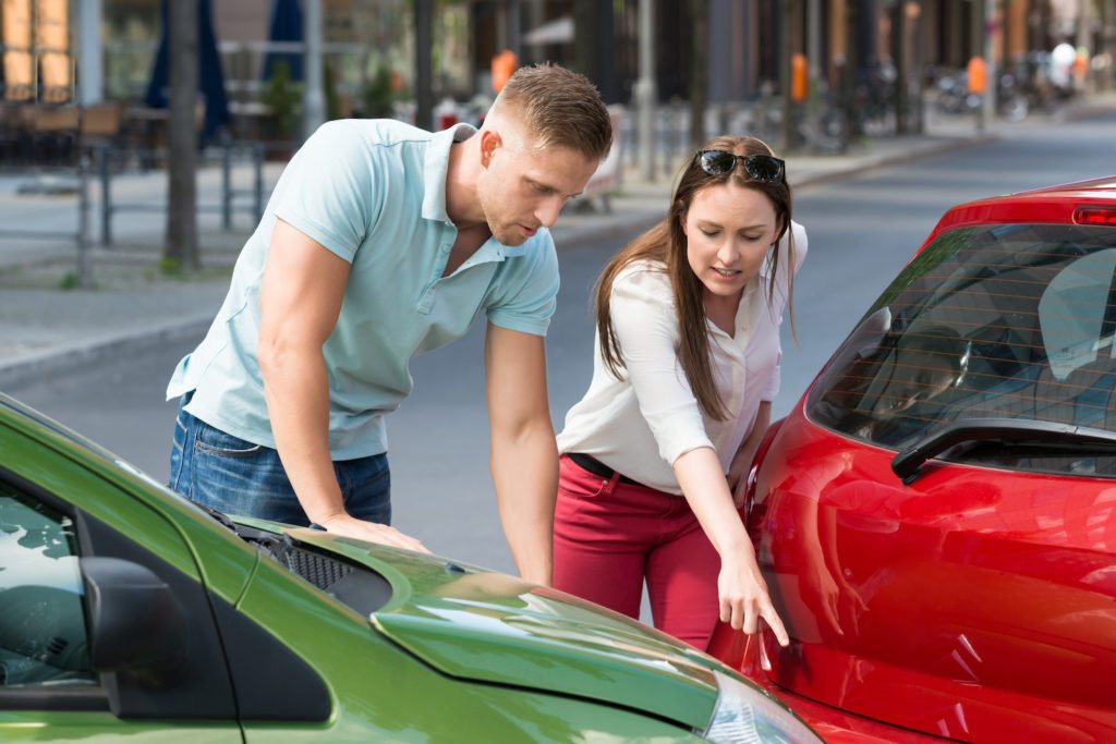 Two drivers discussing their car accident on the street as an example of where California's law of comparative fault would apply