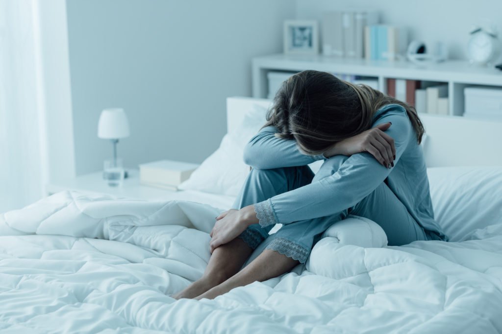 Woman on bed looking distraught