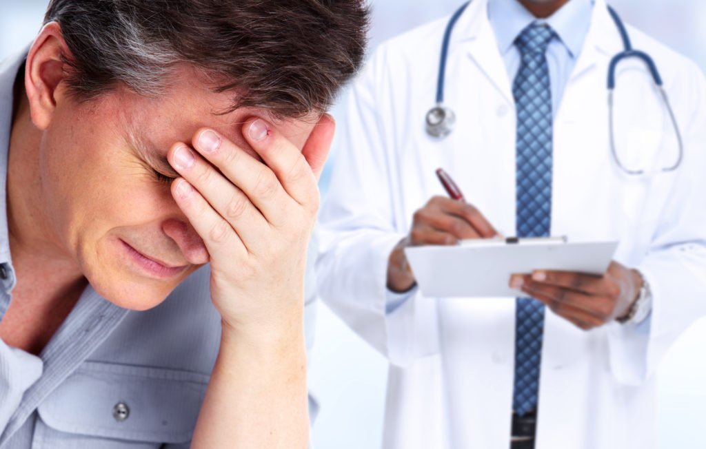 Man looking distraught with doctor in background