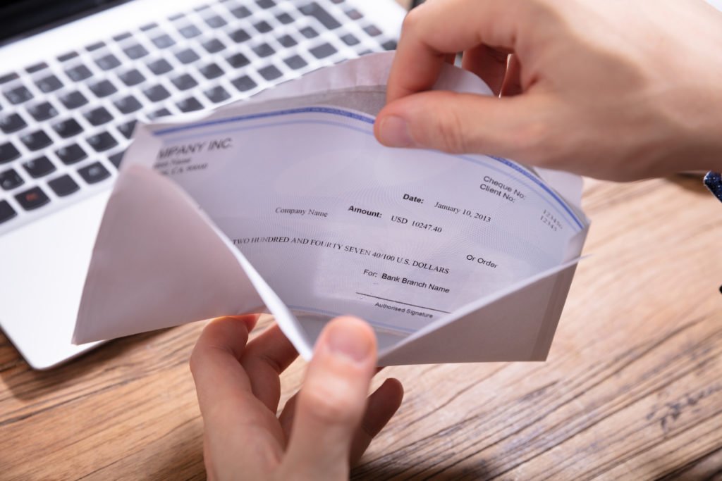 closeup of hands opening envelope holding paycheck