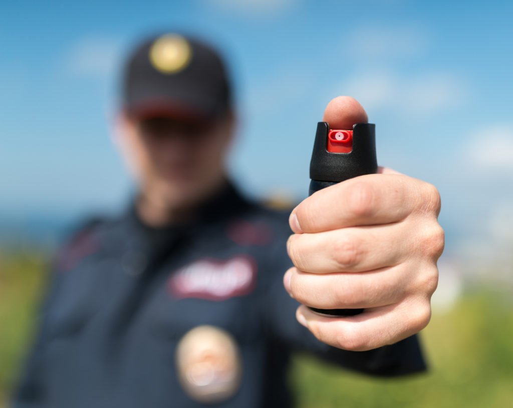 Policeman holding up pepper spray in hand