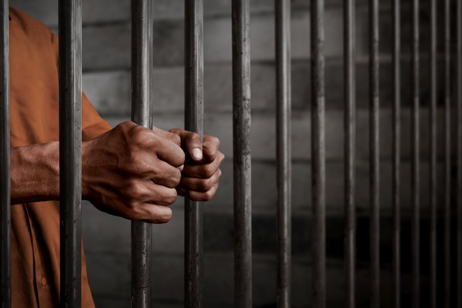 Un recluso agarrando las barras de una celda de la cárcel: una violación del Código de Salud y Seguridad 11361 HS puede llevar a una condena