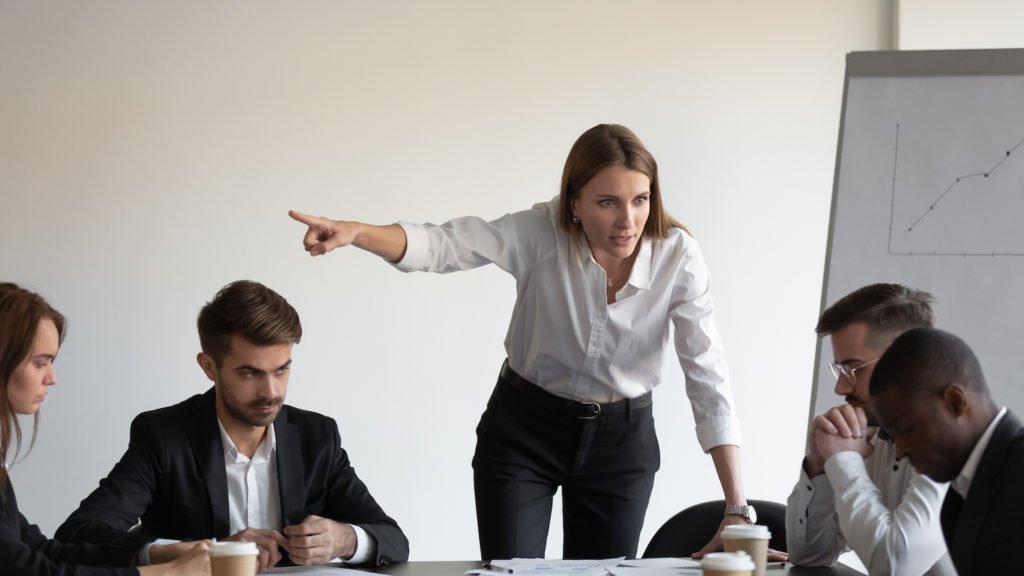 Jefe blanco señalando al empleado negro para que salga de la sala de juntas