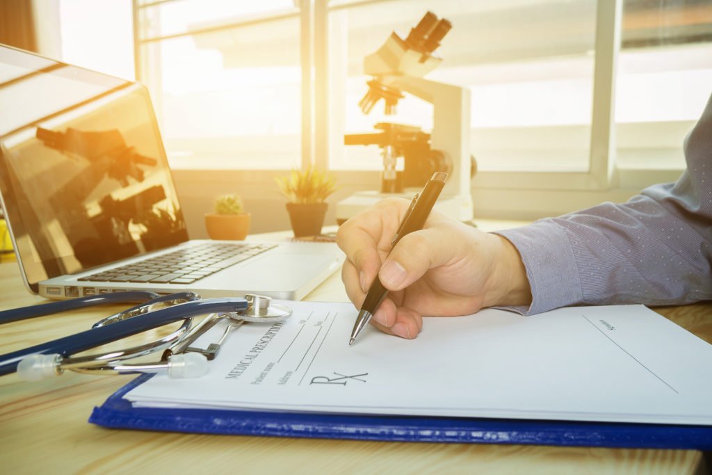 Close-up of hand forging prescription on clipboard