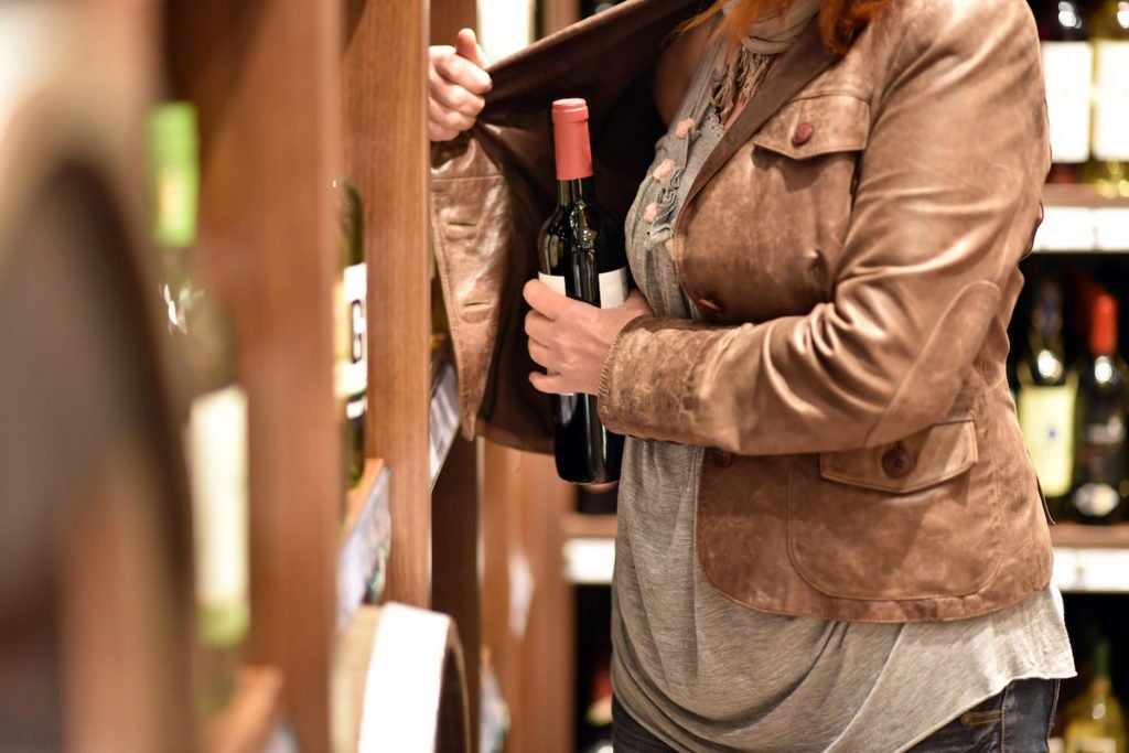 Mujer robando vino de una tienda de paquetes