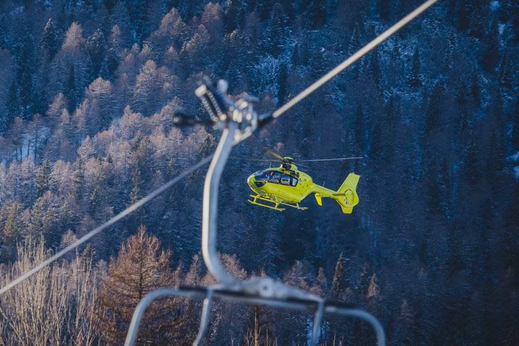 Helicopter flying to a ski lift against backdrop of mountains