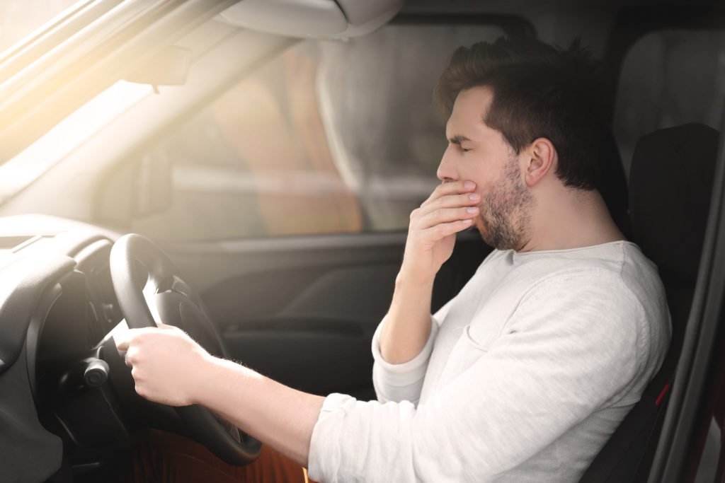 Hombre bostezando mientras está detrás del volante