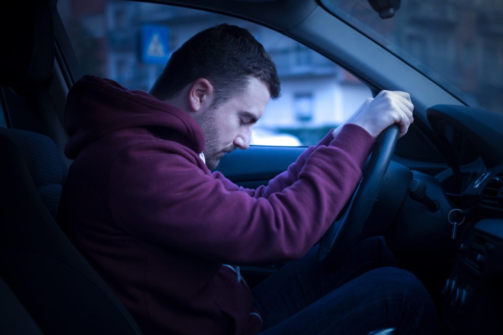 Hombre durmiendo mientras está detrás del volante por la noche