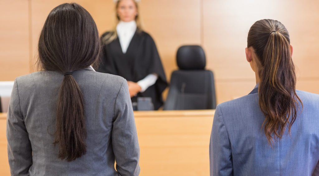 Defense attorney and defendant in foreground with judge in the background