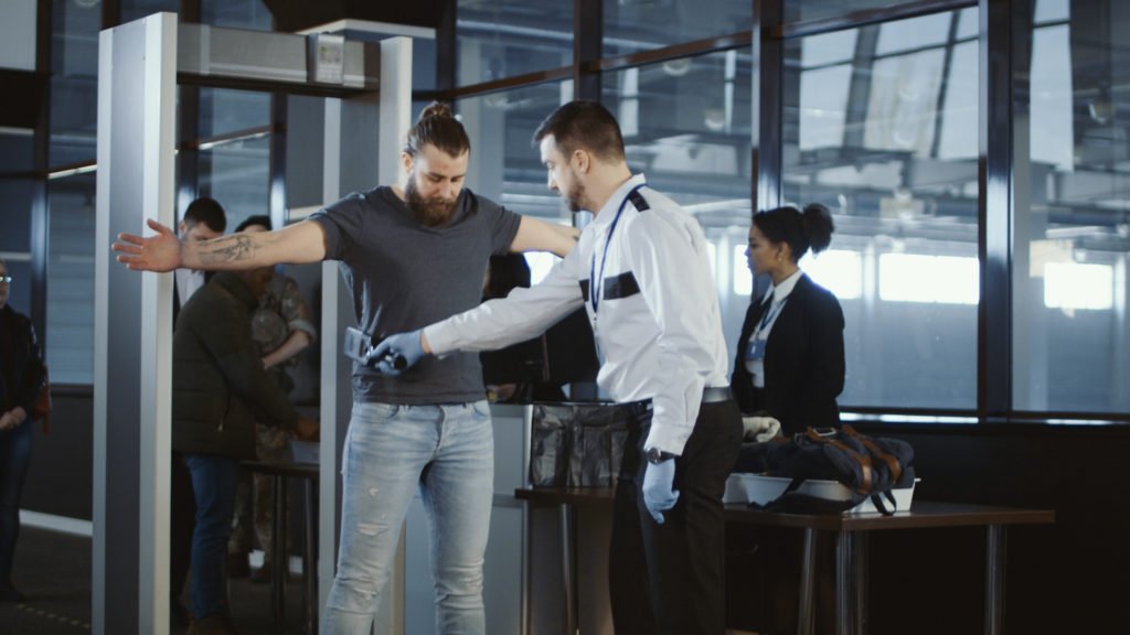 Hombre pasando por el detector de metales y siendo barrido en el aeropuerto