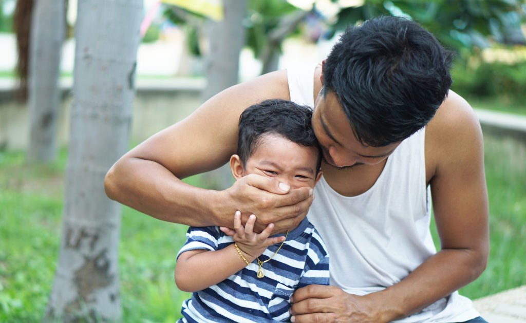 Father holding hand on child's mouth to illustrate parental kidnapping per Colorado 18-3-304 CRS