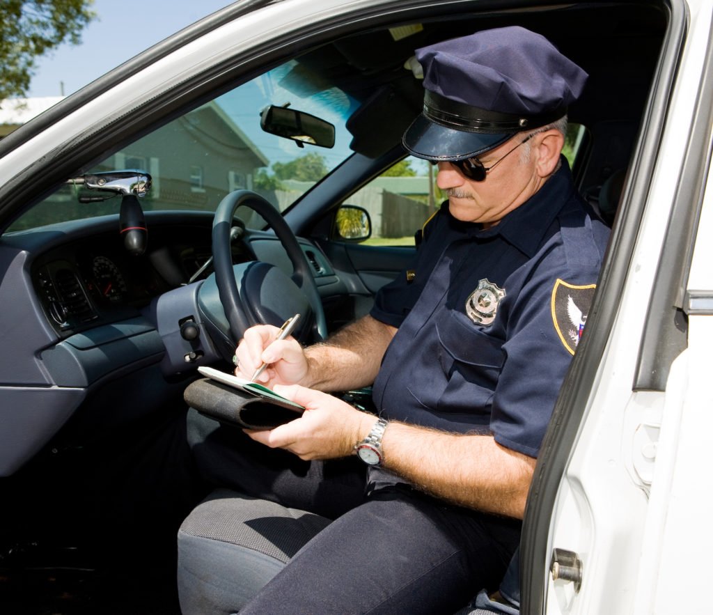 Policeman writing a citation in a police car.