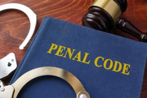 Book that says "Penal Code" with gavel and cuffs