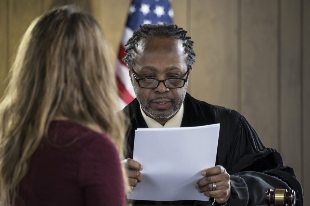 Judge speaking to defendant in front of an American flag