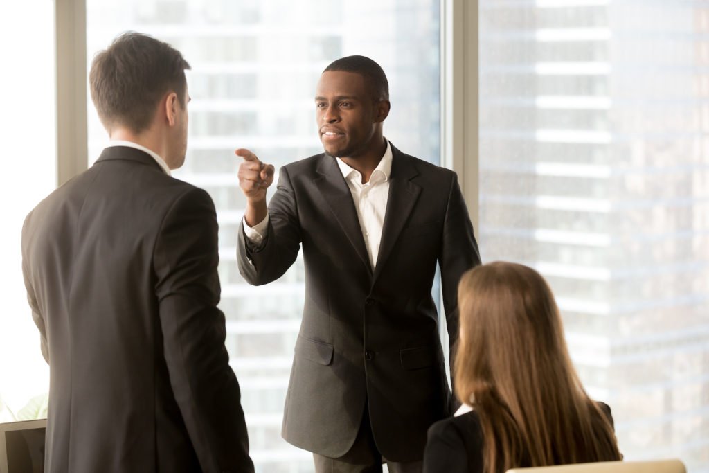 Boss pointing finger at employee during office meeting