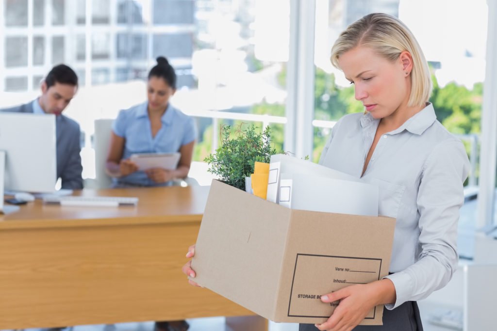 Fired employee holding box of belongings in office