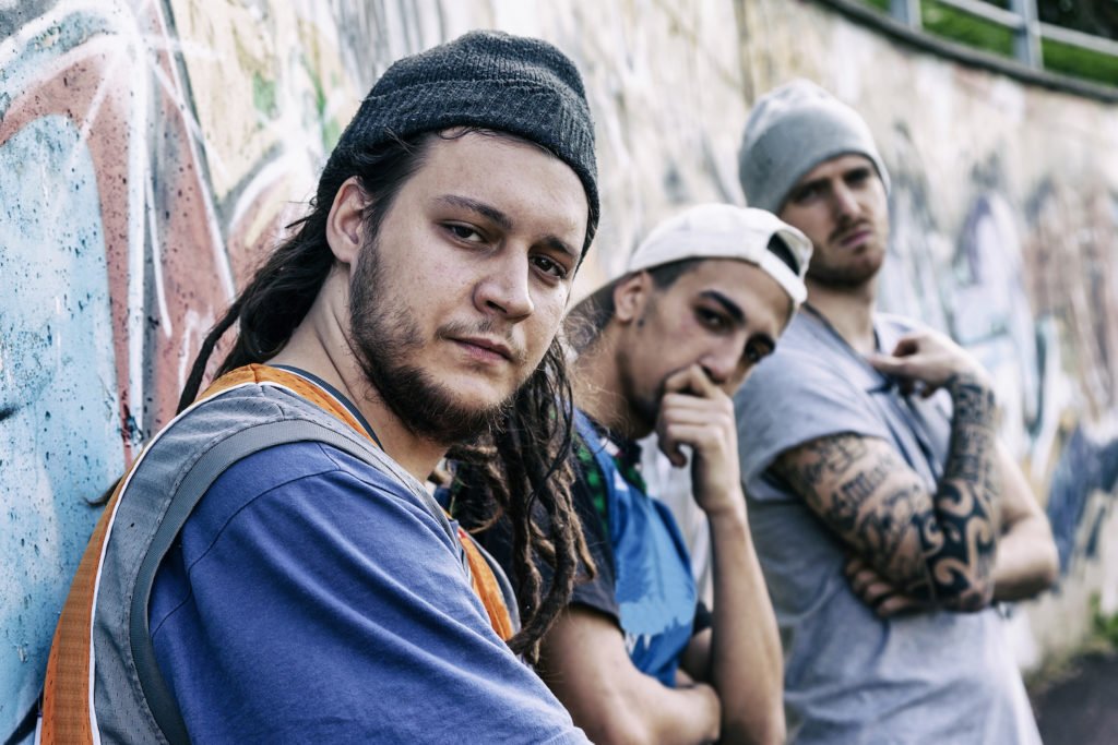 Tres miembros de una pandilla callejera criminal apoyados en una pared